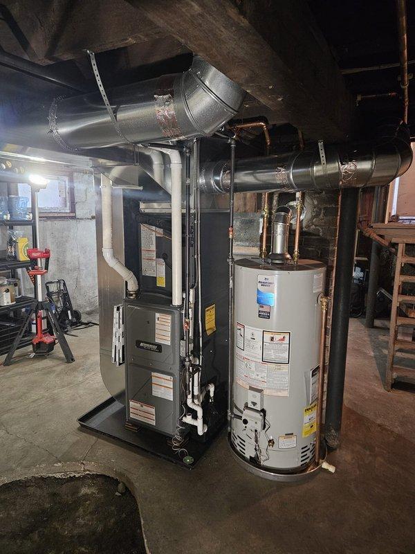 Completed full system installation in basement utility area including new furnace, air conditioning system, and water heater. Installed modern high-efficiency furnace unit with proper venting and ductwork connections, mounted new cylindrical water heater with copper supply lines and appropriate safety labeling, and connected AC system with insulated ductwork running overhead. All equipment properly positioned on concrete basement floor, secured metal ductwork with chain supports, verified all electrical connections, tested system operations, and ensured compliance with manufacturer specifications and local codes.
