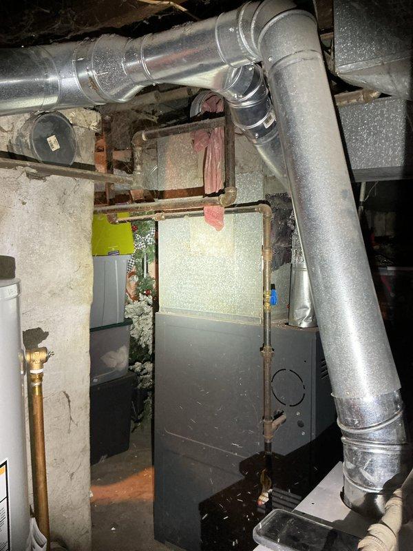 Completed rental inspection for Unit 2, accessing basement mechanical area through lower unoccupied unit using entry code. Performed furnace and water heater inspection, documenting equipment age, brand information, and overall condition. Photographed HVAC system including older heating unit with blue metal cabinet, galvanized ductwork with visible wear and dust accumulation, copper piping, water heater, and associated mechanical components in basement space with exposed joists and insulation.
