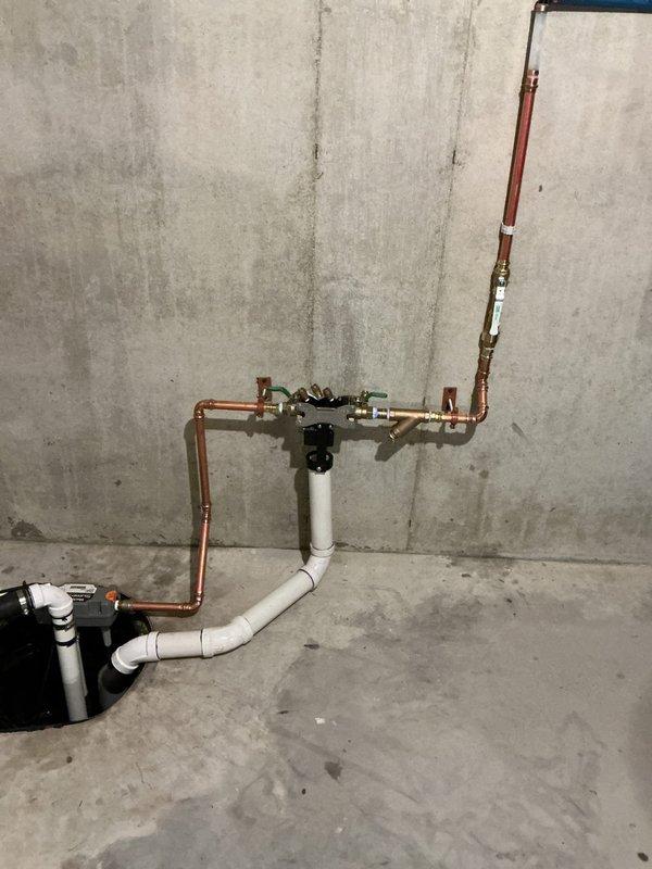 Responded to water backup emergency and installed comprehensive sump pump system with backup protection. Installation included new primary sump pump in basin with dual discharge configuration utilizing PVC and copper piping, complete with check valves, isolation valves, and proper venting. Integrated system with existing plumbing infrastructure, securing all components to concrete foundation wall with appropriate mounting hardware and ensuring proper drainage flow to prevent future basement flooding.
