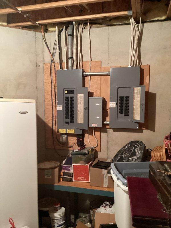 Conducted site assessment for whole-home Generac generator installation at residential property. Evaluated existing electrical infrastructure including two main service panels mounted in basement utility area. Documented current electrical configuration with dual panel setup featuring dedicated generator disconnect switch already labeled "GEN" and main breaker panel with multiple circuits. Assessed available space and clearances in basement area for potential generator transfer switch installation. Reviewed electrical service capacity and panel condition to determine compatibility with automatic standby generator system. Photographed electrical panels, service disconnect, existing conduit pathways, and surrounding utility area to document installation requirements and identify any potential obstacles. Evaluated access points for natural gas or propane fuel line connection and exhaust venting requirements. Determined optimal placement for exterior generator pad and unit positioning rela