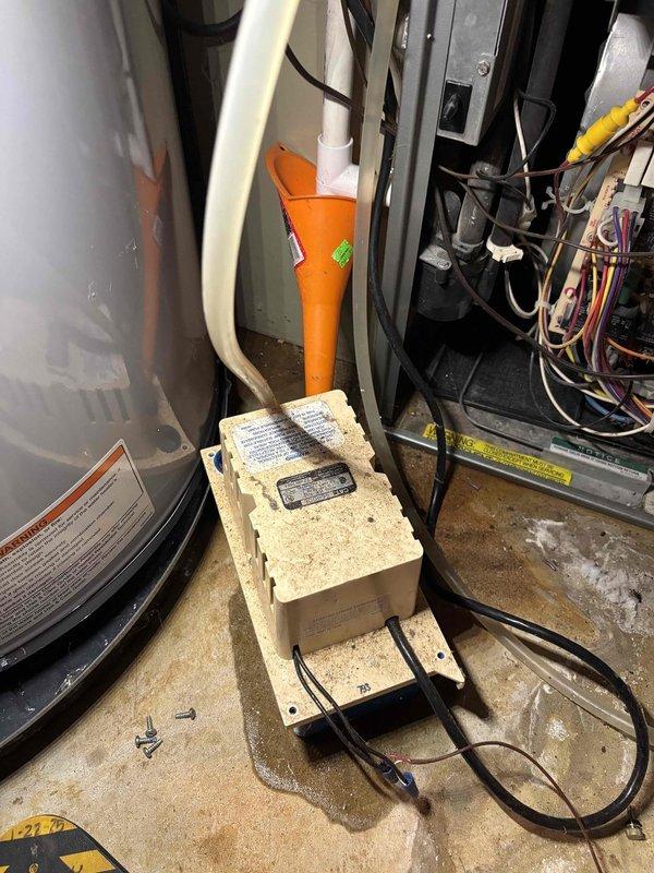 Responded to water leak service call for 15-year-old furnace condensation pump. Upon inspection, confirmed pump was actively leaking while heating system remained operational. Documented existing conditions showing significant corrosion on copper fittings and water staining on concrete floor around pump unit. Photographed condensate pump assembly, associated plumbing connections, and orange PVC discharge piping for service records. Given the age of the pump and active leak condition, recommended pump replacement to prevent further water damage and ensure reliable condensate removal from furnace operation.