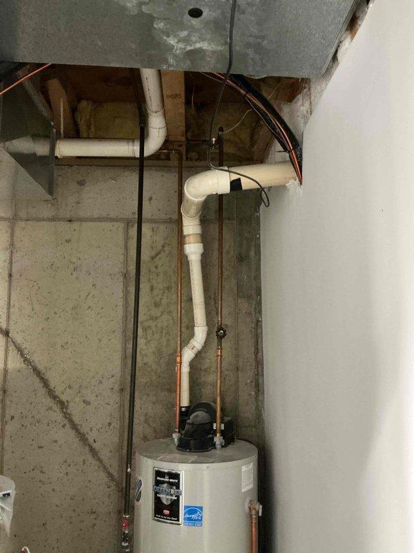 Provided estimate for water heater replacement after previous tune-up failed to resolve ongoing issues with inadequate hot water temperature and spillage. Evaluated existing Energy Star-rated unit in basement mechanical room with associated copper and PVC piping configuration, documented current installation including overhead plumbing runs and venting system, and presented replacement options to address performance concerns.