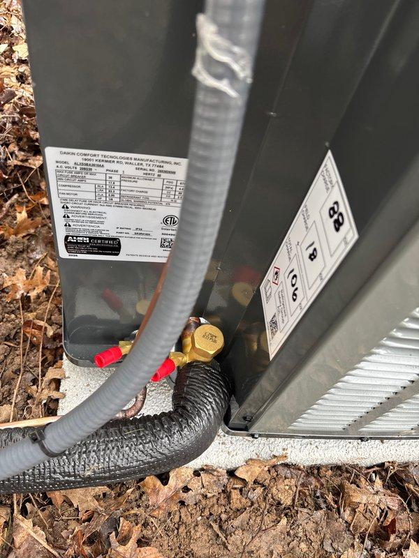 Completed full installation of residential air conditioning system including outdoor condenser unit mounted on concrete pad against exterior wall. Installed and secured all refrigerant lines, electrical connections via junction box, drainage components with PVC piping, and flexible conduit runs. Verified all connections, applied proper sealing and protection to penetrations through building envelope, and confirmed system operational status with appropriate labeling affixed to unit per manufacturer specifications.