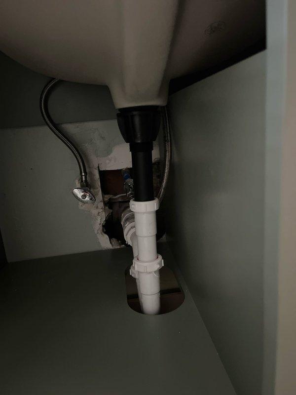 Conducted comprehensive plumbing assessment for new vanity installation, refrigerator ice maker connection, and basement bathroom plumbing issue. Inspected existing under-sink cabinet infrastructure, documenting current drain assembly configuration with white PVC P-trap system and flexible braided supply lines. Evaluated cabinet access points and existing rough-in openings to determine requirements for new vanity plumbing connections, ice maker water supply line routing, and basement bathroom repairs.