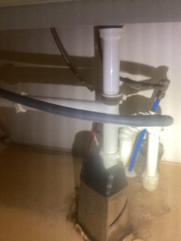 Responded to kitchen plumbing leak issue involving recurring leaks from plastic drain fixtures beneath the sink. Upon inspection, found evidence of water damage and staining on cabinet floor beneath PVC P-trap assembly and drain connections. The existing white PVC drain system and black plastic P-trap showed signs of improper installation or deteriorated seals contributing to the leak problem. Assessed all connections including the dishwasher drain line (gray corrugated hose), supply lines with braided metal flex connections, and shut-off valves. Documented the plumbing configuration and leak damage with photos showing the affected areas and current fixture conditions. Kitchen setup confirmed to have dishwasher connection but no garbage disposal unit present. Identified that the plastic fixtures require replacement or proper reinstallation with new seals to resolve the recurring leak issue and prevent further water damage to cabinetry.