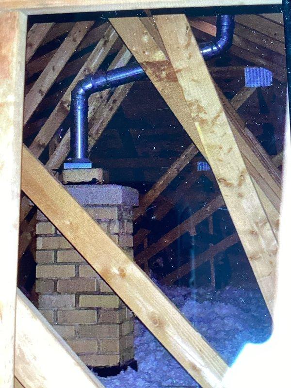 Responded to inspector correction notice requiring chimney liner installation. Documented existing chimney structure in attic space showing brick construction without proper liner system. Photographed current conditions including chimney penetration through roof framing and attic access point to support permit amendment and reinspection scheduling.