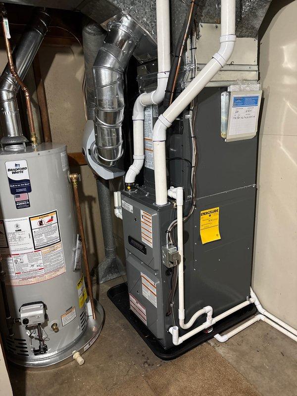 Completed full HVAC system installation including new furnace, air conditioning condenser unit, and Bradford White water heater in residential utility room. Installed Amana brand outdoor condenser unit on concrete pad with proper electrical disconnect, routed refrigerant lines to indoor air handler, and configured all PVC condensate drainage and venting systems. Connected all gas lines, copper water piping, metallic ductwork transitions, and verified proper operation of all newly installed equipment with system startup and testing procedures.