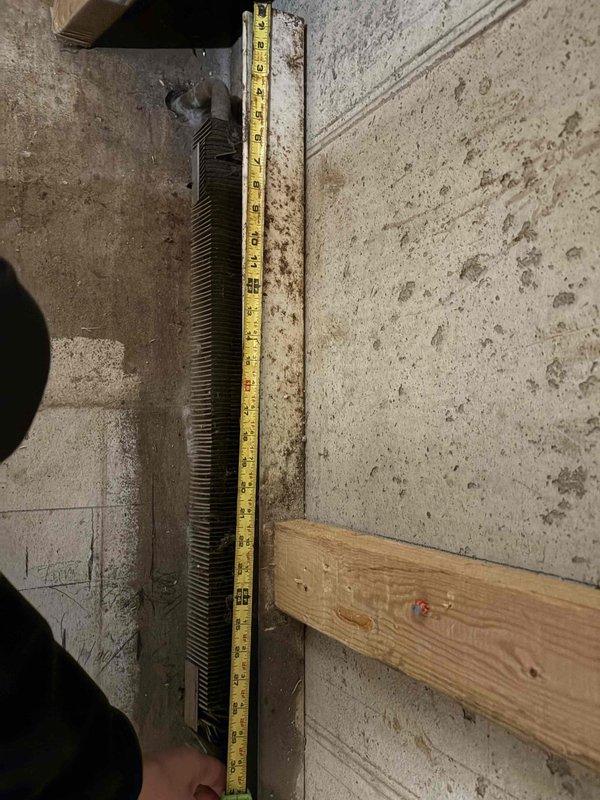 Removed existing baseboard heater from basement wall and properly capped supply and return lines in preparation for room remodeling. Measured and documented wall dimensions for future heater reinstallation once finish work is completed.