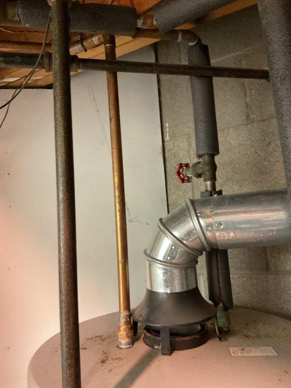 Responded to complaint of rusty water from 10-year-old water heater. Upon inspection, found significant corrosion on water heater system and associated copper plumbing. Documented existing conditions of basement utility area including water heater connections, copper supply lines, and HVAC ductwork routing. Photographed metallic ductwork elbows, copper piping with visible oxidation, red valve control mechanisms, and insulated refrigerant lines for service records. Advised customer that rust-colored water typically indicates deterioration of anode rod or internal tank corrosion in aging water heater units, and recommended replacement evaluation given unit age and symptom severity.