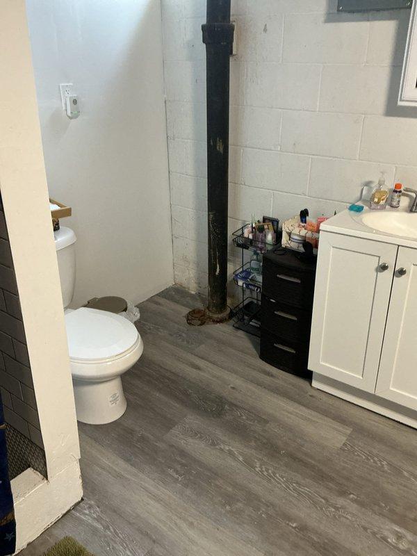 Responded to basement drain backup following storm event. Upon arrival, found water leaking from drain line connections in basement bathroom area. Inspected the drainage system and identified compromised connection points on vertical drain stack. Assessed the extent of water intrusion and documented existing conditions including aging cast iron pipe with deteriorated base flange. Cleared the backed-up drain line and secured leaking connections to restore proper drainage function. Verified system was flowing correctly with no additional leakage at connection points upon completion.