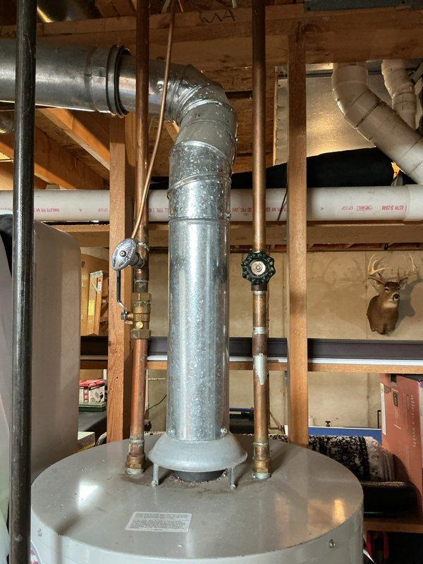 Responded to report of water heater and furnace leaking in basement. Upon inspection, examined 12-year-old Carrier furnace and 17-year-old Bradford White water heater. Documented existing plumbing connections, copper supply lines with shutoff valves, and galvanized flue pipe configuration. Photographed water heater installation, surrounding ductwork, and mechanical room conditions to assess potential leak sources and equipment status.