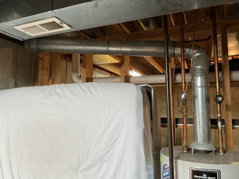 Responded to report of water heater and furnace leaking in basement. Upon inspection, examined 12-year-old Carrier furnace and 17-year-old Bradford White water heater. Documented existing plumbing connections, copper supply lines with shutoff valves, and galvanized flue pipe configuration. Photographed water heater installation, surrounding ductwork, and mechanical room conditions to assess potential leak sources and equipment status.