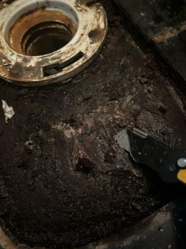 # Toilet Replacement and Repair

Removed and replaced deteriorated toilet due to extensive water damage to the subfloor and mounting area. The existing fixture had caused significant moisture infiltration, resulting in severe wood rot and structural degradation of the flooring beneath. Disconnected water supply line and removed corroded closet flange assembly showing heavy rust and mineral buildup.

Assessed subfloor damage and addressed compromised wooden planks exhibiting blackened discoloration and decay from prolonged moisture exposure. Removed affected flooring sections and prepared surface for new installation. Cleaned and scraped mounting area to remove accumulated debris, corrosion, and deteriorated material around drain opening.

Installed new wax ring seal and secured toilet to repaired mounting surface. Reconnected water supply line and tested for proper function and seal integrity. Verified no leaks at connection points and confirmed proper drainage operation. Restored area