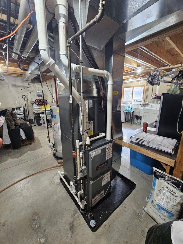 Completed full HVAC system replacement including new furnace and air conditioning unit. Installed modern furnace with matching evaporator coil in basement mechanical room, configured all PVC condensate drain lines and venting pipes, connected black flexible ductwork to existing distribution system, and mounted equipment on protective pad. Installed new outdoor condensing unit in backyard, ran refrigerant lines through window opening, completed all electrical connections including conduit installation, and performed system startup with refrigerant charging using manifold gauges. Verified proper operation of both heating and cooling systems.