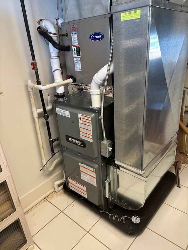 Completed full furnace installation at residential property, replacing existing heating system with new Carrier brand unit. Installation included mounting and securing furnace unit, connecting all necessary ductwork and sheet metal plenum, routing copper refrigerant lines, installing white PVC condensate drainage piping with proper fittings and valves, running electrical conduit and wiring, and positioning condensate drain pan at equipment base. All components properly mounted, sealed, and tested for operational functionality per manufacturer specifications.