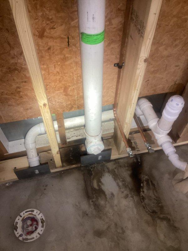 Responded to a water leak originating from PVC plumbing behind a bathroom wall. Upon inspection, identified compromised piping in the concealed plumbing chase with visible water damage and staining on the concrete floor below. Repaired the defective section of the drainage system by replacing the damaged PVC pipe segment and installing a new rubber coupling with stainless steel hose clamps to ensure a watertight seal. Verified all connections were secure and tested the system to confirm the leak was resolved.