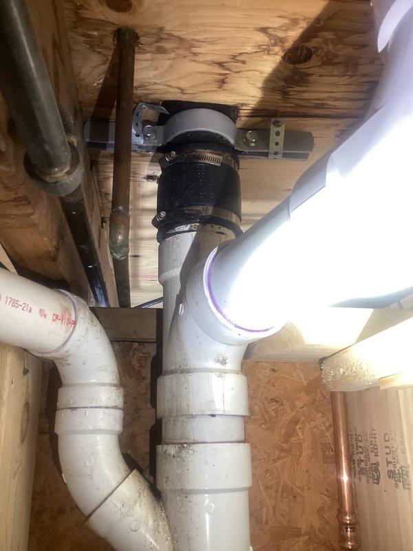 Responded to a water leak originating from PVC plumbing behind a bathroom wall. Upon inspection, identified compromised piping in the concealed plumbing chase with visible water damage and staining on the concrete floor below. Repaired the defective section of the drainage system by replacing the damaged PVC pipe segment and installing a new rubber coupling with stainless steel hose clamps to ensure a watertight seal. Verified all connections were secure and tested the system to confirm the leak was resolved.