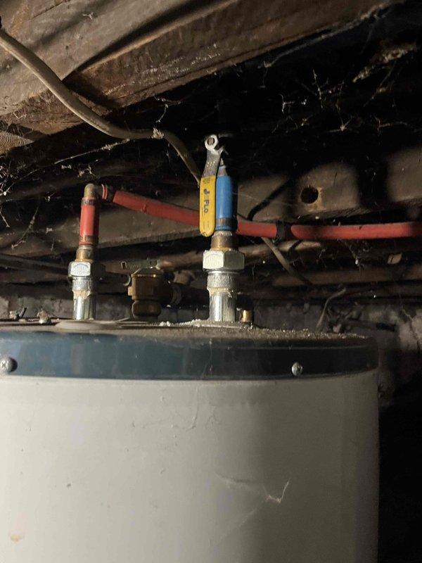 Responded to service call for no hot water condition. Inspected water heater installation in crawl space and verified proper operation of inlet/outlet isolation valves with red and blue handles. Confirmed water supply connections and plumbing infrastructure were intact with no visible leaks or damage to flexible supply lines or surrounding pipe work.