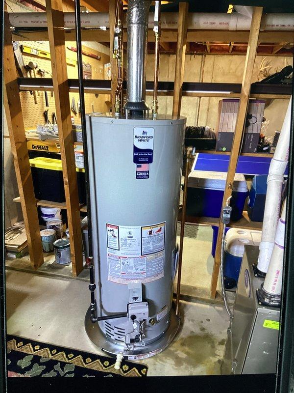 Completed water heater installation in residential basement utility area. Installed new cylindrical water heater unit with proper metallic exhaust venting system, ensured all manufacturer specifications and safety requirements were met, and verified system operational status with alarm cleared confirmation.