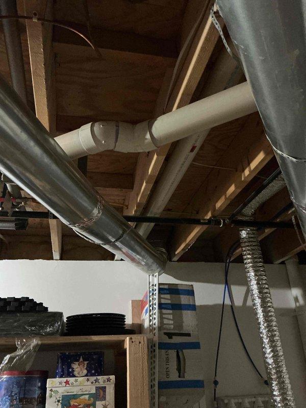 Conducted site assessment for water heater replacement in residential property. Evaluated existing installation location in utility area with exposed ceiling joists, documented current plumbing configuration including white PVC venting system and existing ductwork routing, and provided comprehensive estimates for both traditional tank-style and tankless water heater options to customer for consideration.