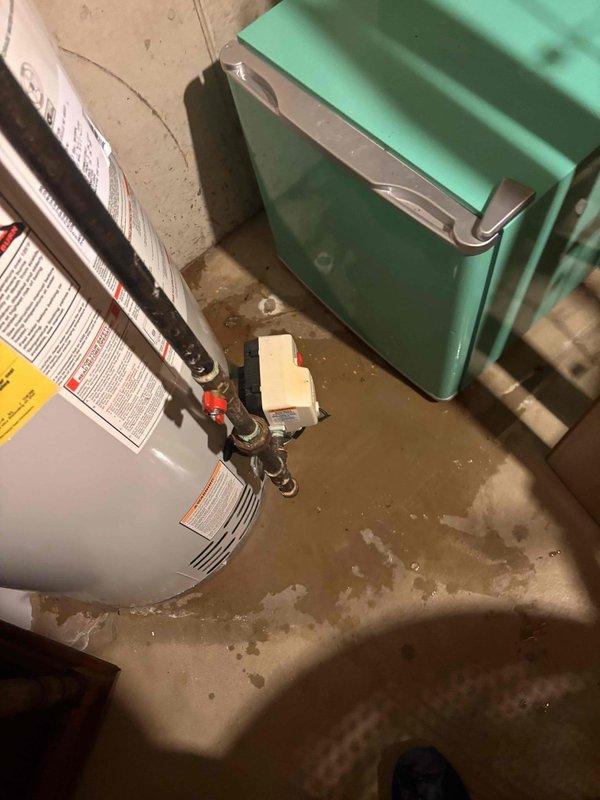 Responded to early availability call for leaking water heater. Upon arrival, inspected 18-year-old water heater located in basement utility area and confirmed active leak with visible water staining on concrete floor beneath unit. Documented equipment condition with photos showing water heater installation, surrounding mechanical equipment including boiler system, and overhead plumbing infrastructure with PVC utility lines. Assessed unit age and leak severity to provide customer with repair versus replacement recommendations given the advanced age of the equipment beyond typical service life expectancy.