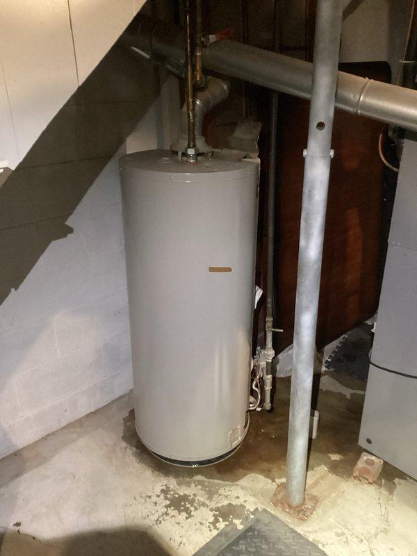 Responded to water heater leak on 12-15 year old A.O. Smith unit. Upon inspection, observed water staining and discoloration on concrete floor surrounding base of water heater, confirming active leak. Documented existing plumbing configuration including copper supply lines, brass fittings, temperature and pressure relief valve, and connection points. Photographed unit and surrounding area showing leak evidence and overall system condition. Given age of unit and active leak, provided assessment and recommendations for repair or replacement options.