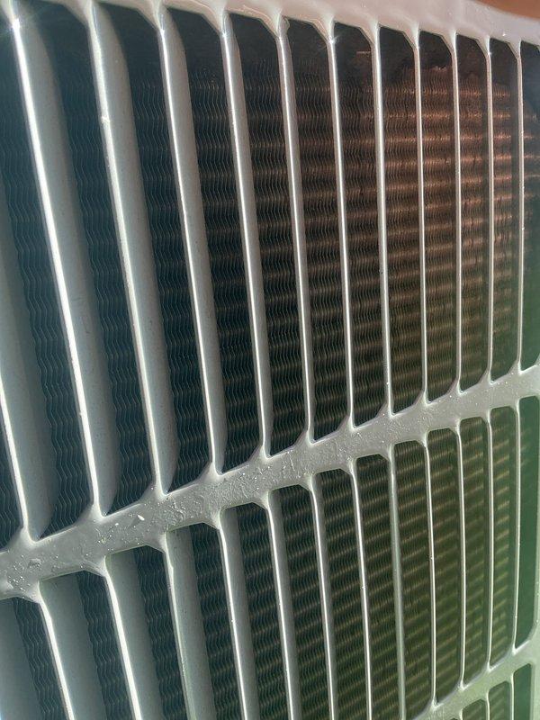 Completed annual cooling maintenance on Carrier air conditioning system. Performed comprehensive tune-up inspection of outdoor condenser unit, which was found to be in good operating condition with clean coils and proper airflow through the heat exchanger fins. Verified condenser unit is level on concrete pad with adequate clearance and maintained surroundings. Inspected protective grille and cabinet housing, noting normal weathering with no structural damage or deterioration. Examined heat exchanger coils and fins, confirming proper condition and heat transfer capability. Unit shows signs of regular maintenance with no immediate service concerns identified. System operational and ready for cooling season.