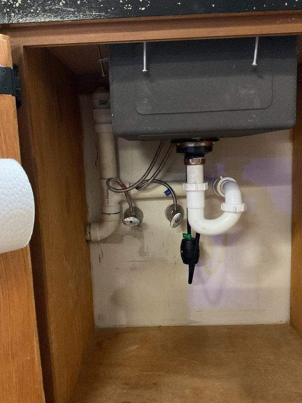 Reworked lavatory sink drain system and installed Air Admittance Valve (AAV) to resolve drainage issues. Reconfigured existing white PVC P-trap assembly under sink, ensuring proper trap seal and drainage flow. Installed AAV to provide necessary venting where conventional vent stack was not accessible. Verified all connections are secure, leak-free, and meet code requirements for proper drain-waste-vent function.