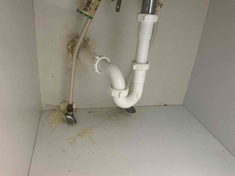 Responded to service call for leaking bathroom sink faucet. Upon inspection, identified worn cartridge and deteriorated supply line connections causing water seepage into vanity cabinet, evidenced by visible water staining on cabinet surfaces. Replaced faulty faucet cartridge, tightened supply line connections, and tested system under full water pressure to verify leak elimination and proper operation of single-handle faucet assembly.