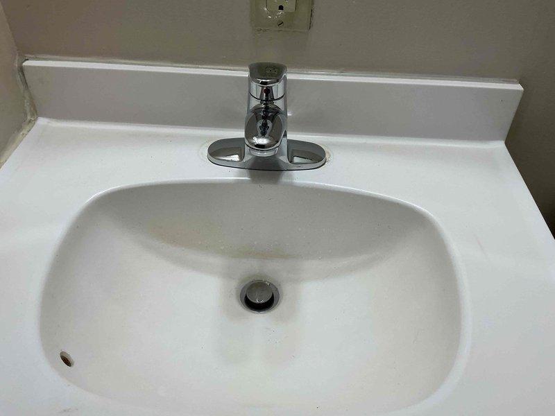 Responded to service call for leaking bathroom sink faucet. Upon inspection, identified worn cartridge and deteriorated supply line connections causing water seepage into vanity cabinet, evidenced by visible water staining on cabinet surfaces. Replaced faulty faucet cartridge, tightened supply line connections, and tested system under full water pressure to verify leak elimination and proper operation of single-handle faucet assembly.