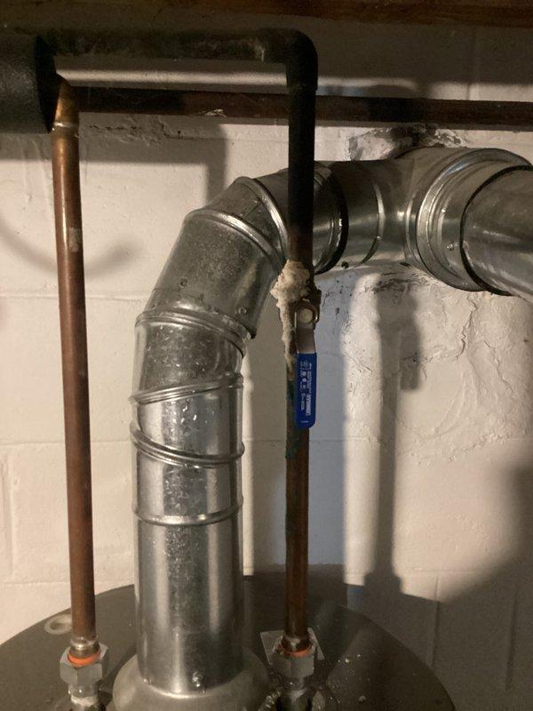 Responded to service call for water heater failure with complete loss of hot water following flooding event. Upon arrival, assessed 12-year-old water heater unit and surrounding mechanical area showing significant water damage, debris accumulation, and corrosion on metal components. Documented existing conditions including compromised flooring, rust damage to equipment base, and deteriorated materials in confined mechanical space. Inspected plumbing connections, copper piping, PVC drain lines, and ductwork assembly for flood-related damage. Photographed installation against block wall foundation and equipment positioning for service records. Unit deemed non-operational due to flood exposure and age-related deterioration requiring replacement recommendation.