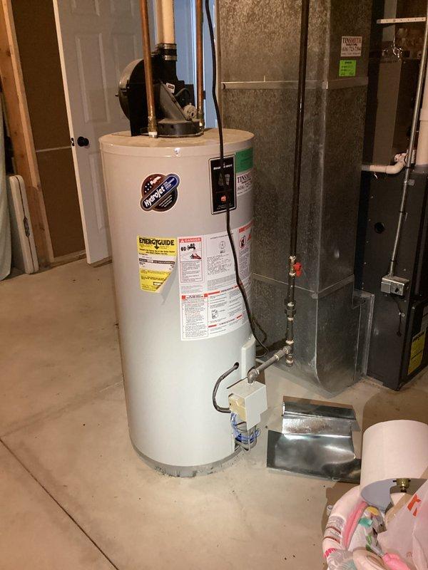 Provided estimate for replacement of 21-year-old Bradford White water heater located in unfinished basement utility area. Unit assessed with existing copper supply piping, expansion tank, and metal drip pan; documented current installation configuration including proximity to HVAC equipment and existing plumbing connections for replacement planning purposes.