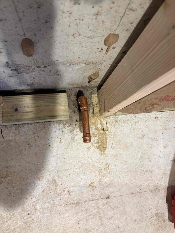 Completed third visit to address persistent leaking at new copper pipe connection caps on 13-year-old Utica boiler system. Previous cap installations continued to leak despite multiple attempts. Inspected copper piping penetration through basement ceiling, assessed elbow joint connections at floor level, and evaluated oxidized copper fittings showing weathered patina. Replaced defective caps with proper fittings to achieve leak-free seal. Verified all connections were secure and tested system for proper operation. Documented installation with photos showing pipe routing through wooden framing and concrete foundation area.