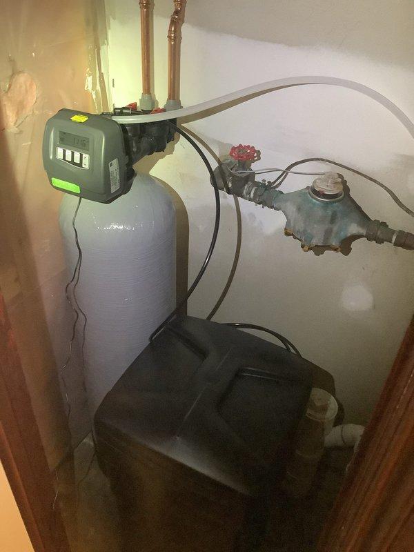 Completed installation of Sterling SWS1-60 water softener system in residential utility area. Installation included mounting the main softener tank with digital control head, connecting inlet and outlet copper plumbing lines, installing bypass valve assembly with shutoff capability, and positioning brine tank for salt storage. All plumbing connections were completed using existing copper supply lines, system was programmed and tested for proper operation.