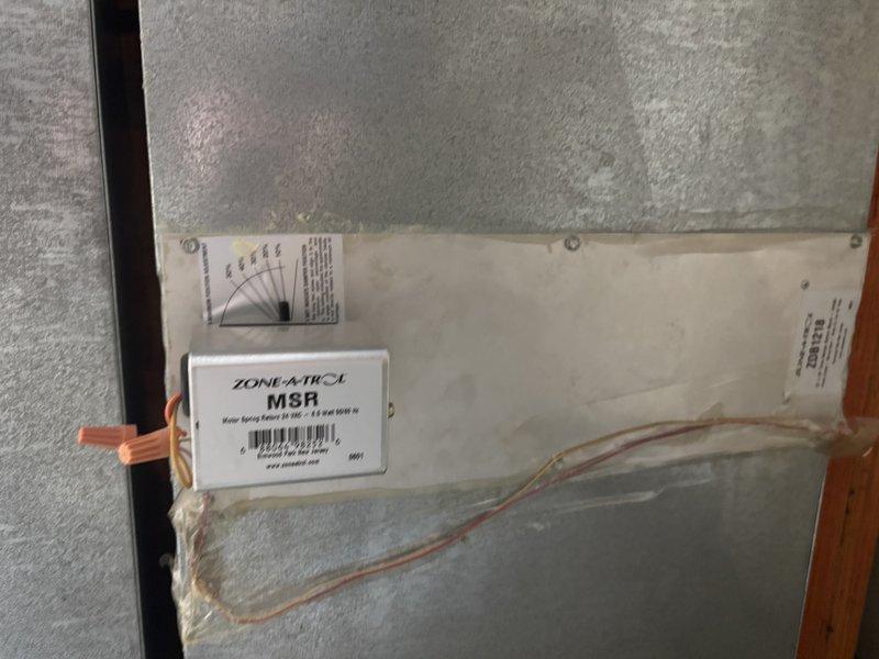 Completed furnace super tune-up on Bryant HVAC system. Inspected air filter housing and found pleated air filter with accumulated dust and debris requiring replacement. Noted visible rust and corrosion on metal housing panel surrounding filter assembly. Examined Zone-A-Trol M8R motor spring return control module with 24 VAC operation, verified wiring connections secured with wire nuts, and confirmed proper installation within air handler unit. Inspected condensate drainage system including white PVC piping and brass valve connections. All accessible components photographed and system operational upon completion of tune-up procedures.