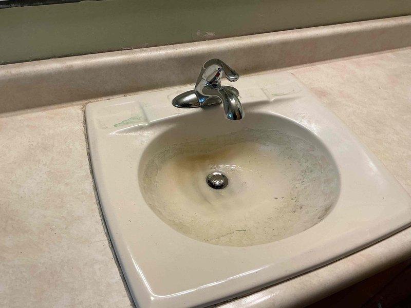 Responded to service call for bathroom faucet experiencing intermittent dripping for approximately one year in a fifty-year-old residential property. Upon inspection, identified worn internal valve components and corroded supply line connections beneath the sink as the primary causes of the leak. Disassembled faucet assembly, replaced deteriorated cartridge and seals, and addressed corroded metal fittings showing greenish-blue oxidation. Verified proper operation of single-handle chrome faucet and pop-up drain assembly. Tested water flow and confirmed complete elimination of dripping issue. System restored to full functionality with no leaks detected at completion.