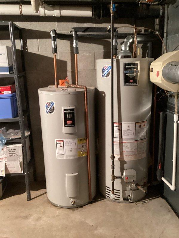 Responded to service call for water heater not producing hot water with possible pilot light issue. Upon inspection, found dual water heater installation in basement utility area consisting of one white conventional water heater and one gray/silver unit. Assessed both units for operational status, checked pilot light assembly, and verified gas supply and ignition systems. Photographed installation showing copper supply lines with black flexible connectors, PVC venting system, and overall equipment configuration for documentation purposes.

Additionally addressed bathroom plumbing concerns including frozen shutoff valve at sink requiring replacement and dripping faucet. Evaluated valve condition and prepared replacement recommendations. Documented complete plumbing system layout including water heater connections, pressure tank, and associated piping infrastructure. All findings and equipment conditions recorded through photographic documentation for service records and future reference