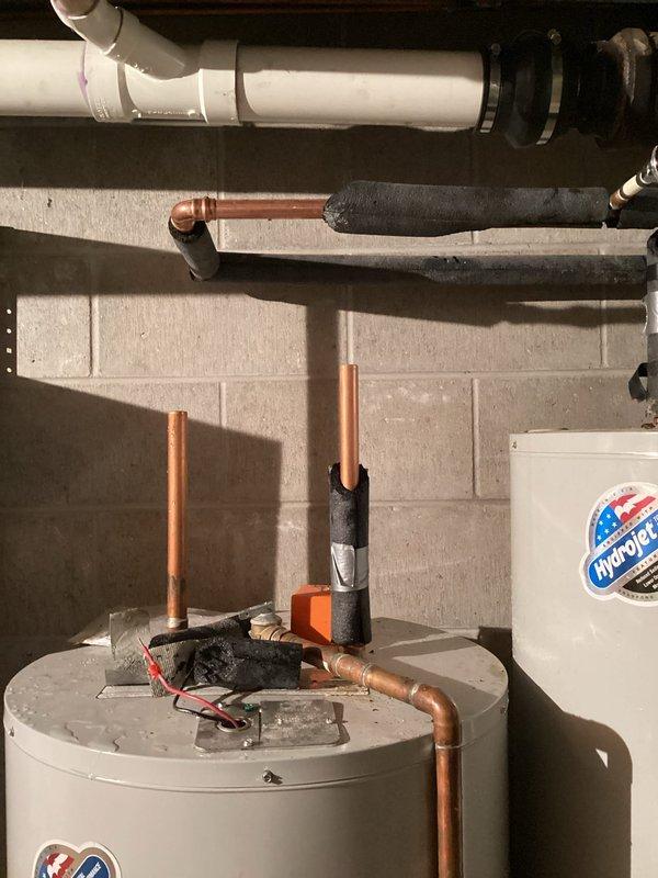 Responded to service call for water heater not producing hot water with possible pilot light issue. Upon inspection, found dual water heater installation in basement utility area consisting of one white conventional water heater and one gray/silver unit. Assessed both units for operational status, checked pilot light assembly, and verified gas supply and ignition systems. Photographed installation showing copper supply lines with black flexible connectors, PVC venting system, and overall equipment configuration for documentation purposes.

Additionally addressed bathroom plumbing concerns including frozen shutoff valve at sink requiring replacement and dripping faucet. Evaluated valve condition and prepared replacement recommendations. Documented complete plumbing system layout including water heater connections, pressure tank, and associated piping infrastructure. All findings and equipment conditions recorded through photographic documentation for service records and future reference