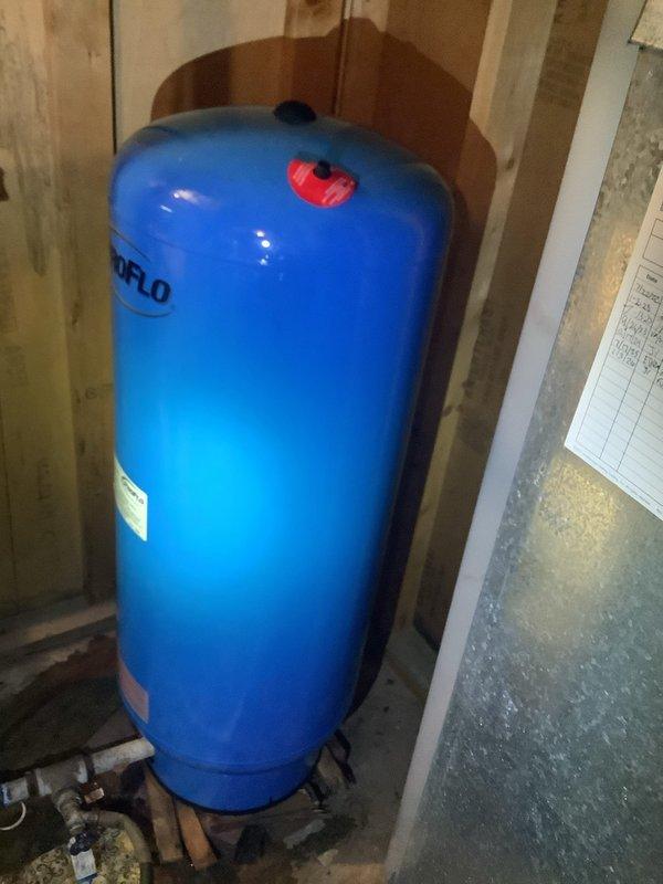 Replaced failed 32-gallon bladder pressure tank with new ProFlo unit in residential mechanical room. Installed tank on metal base platform, secured with strapping to wall studs, and reconnected all plumbing connections including braided supply lines and PVC piping to restore proper water pressure system operation.
