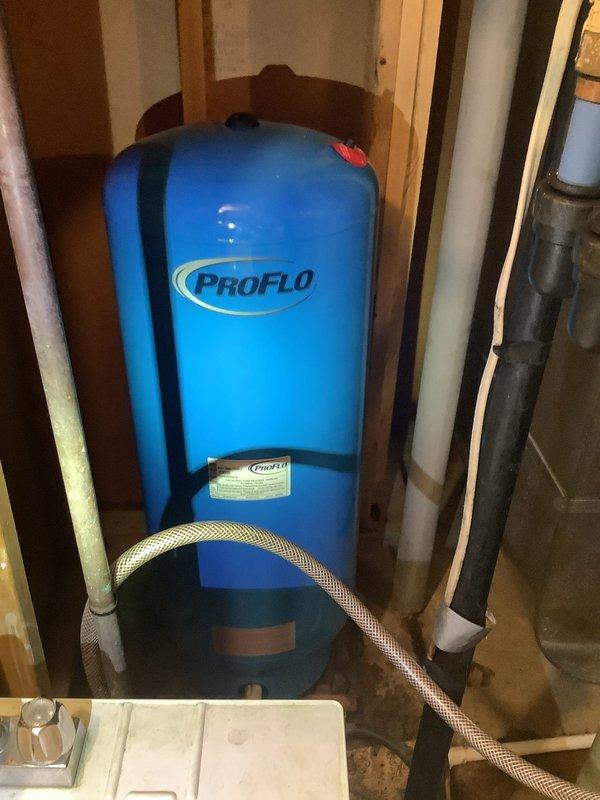 Replaced failed 32-gallon bladder pressure tank with new ProFlo unit in residential mechanical room. Installed tank on metal base platform, secured with strapping to wall studs, and reconnected all plumbing connections including braided supply lines and PVC piping to restore proper water pressure system operation.