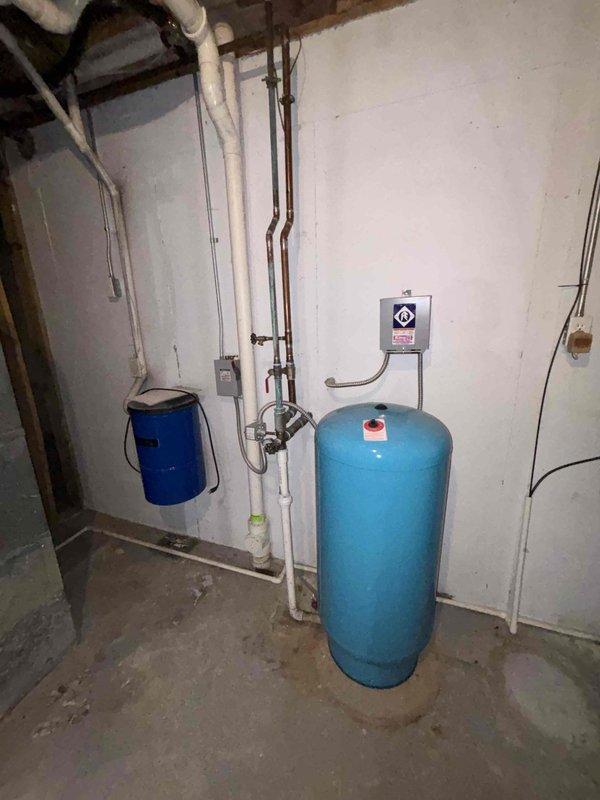 Responded to complaint of extended hot water delivery time (10-15 minutes) and low water pressure throughout residence. Inspected water heater, pressure tank, and associated plumbing system in basement utility area. Diagnosed issue with pressure tank system affecting both hot water circulation and overall water pressure. Tested pressure switch settings, checked tank pre-charge pressure, and verified water heater operation. Adjusted pressure tank settings and system controls to restore proper water pressure and reduce hot water wait time. Verified improvements to water flow and temperature delivery at multiple fixtures throughout the home.