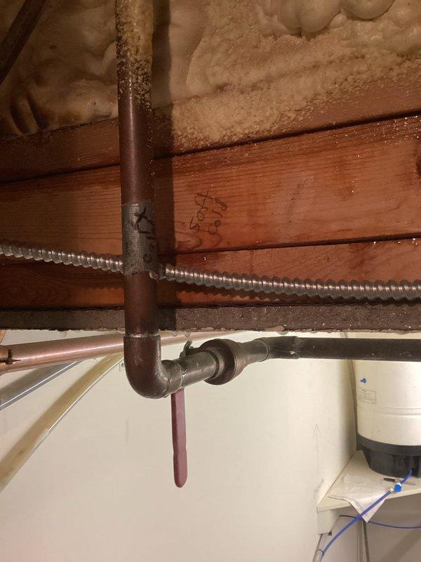 Responded to plumbing leak emergency where water supply had been shut off due to active leak. Upon inspection, identified leak in Charlotte Pipe FlowGuard CPVC water supply line running through exposed ceiling/attic space near spray foam insulation and wooden joists. Performed pipe repair to damaged section of water line showing discoloration and failure point. Restored water supply and verified system integrity with no additional leaks detected. Also inspected aging copper piping in basement area near water heater to ensure no secondary leak sources were present.