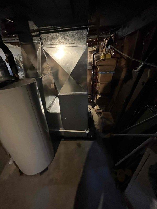 Successfully completed full furnace installation in basement utility area. New gray furnace unit was positioned and secured with metallic exhaust venting installed and routed upward through ceiling joists. All ductwork connections were completed, including plenum attachment and distribution system integration. System was tested for proper operation, airflow verified, and all safety checks performed to ensure code compliance.
