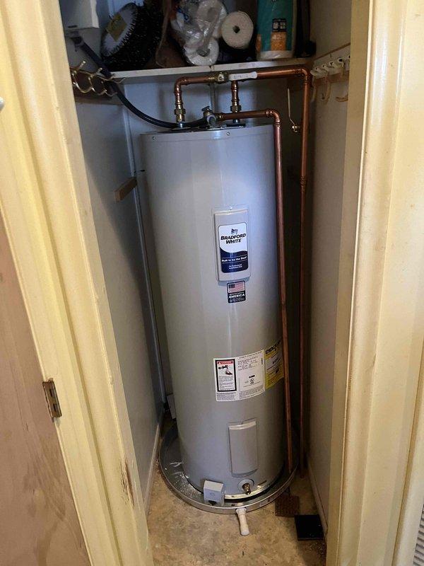 Successfully completed installation of residential water heater unit in utility closet space. Installed new water heater with proper copper piping connections, brass fittings, and valves at top of unit, along with flexible connector hose. Ensured unit was properly positioned on existing tile flooring with appropriate base support and verified all plumbing connections were secure and leak-free.