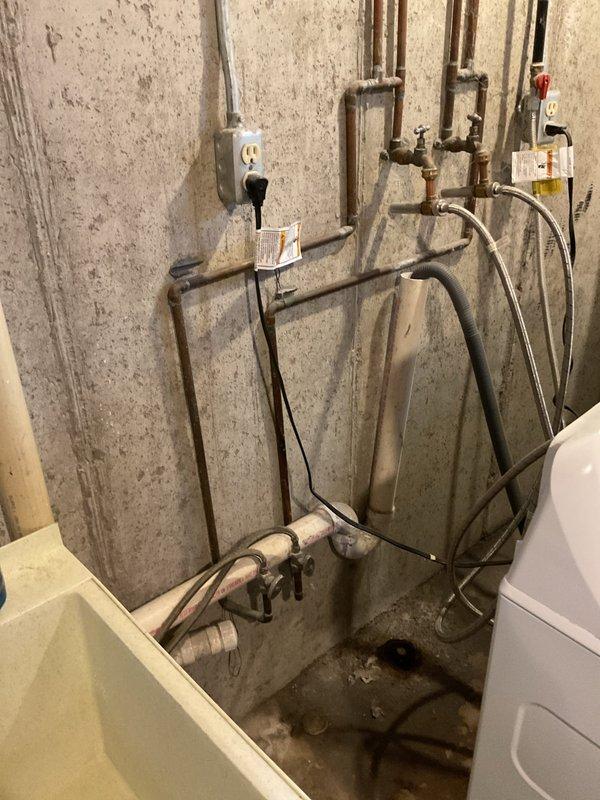 Responded to drain backup issue in finished basement near laundry area. Upon arrival, inspected plumbing system and reviewed previous camera scope findings from November that showed no blockages. Assessed exposed copper piping network, valves, and drainage connections mounted on basement walls. Examined floor drain area where dark staining and moisture were visible at wall-floor junction, indicating previous or ongoing drainage concerns. Documented existing plumbing infrastructure including PVC drainage lines and mechanical connections. Customer advised that backup issues persisted despite clear camera inspection results, suggesting potential issue with drain slope, venting, or fixture-specific problem rather than main line blockage.