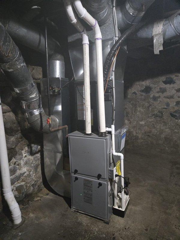 Successfully completed add-on air conditioning system installation to existing forced-air heating system. Installed new outdoor condensing unit on concrete pad adjacent to building exterior with proper electrical disconnect and conduit routing through exterior wall. Connected refrigerant lines and integrated new evaporator coil with existing furnace and ductwork in basement mechanical room. Installed PVC condensate drain lines and completed all necessary refrigerant piping connections between indoor and outdoor components. Verified proper airflow through existing duct system, tested electrical connections at disconnect box, and confirmed system operation. All work performed per manufacturer specifications and local code requirements.