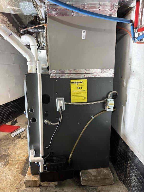 Completed installation of high-efficiency Goodman HVAC system in residential mechanical room, including 96.1 AFUE furnace unit with proper electrical disconnects and PVC venting. Installed and connected all ductwork, condensate drainage system, and verified proper clearances on concrete pad with protective matting. System tested and operational with all manufacturer safety labels and documentation posted per code requirements.