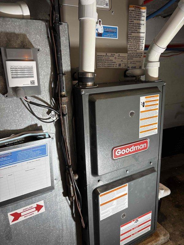 Completed installation of high-efficiency Goodman HVAC system in residential mechanical room, including 96.1 AFUE furnace unit with proper electrical disconnects and PVC venting. Installed and connected all ductwork, condensate drainage system, and verified proper clearances on concrete pad with protective matting. System tested and operational with all manufacturer safety labels and documentation posted per code requirements.