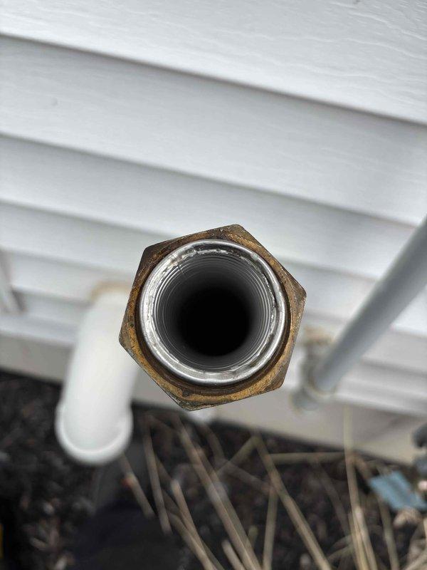 Responded to emergency gas leak on exterior gas line between meter and house. Upon arrival, confirmed utility company had shut off gas supply due to active leak, leaving property without heat or hot water. Conducted thorough inspection of exterior gas piping system and identified significant corrosion and rust at multiple threaded pipe connections, particularly at elbow fittings on the black iron pipe assembly. The deteriorated fittings showed extensive oxidation from prolonged weather exposure, compromising the integrity of the gas line connections. Documented all affected areas with photographs showing corroded brass/bronze fittings and rusted connection points on the vertical and horizontal pipe runs mounted to building exterior. Advised customer of necessary repairs to restore safe gas service to the property.
