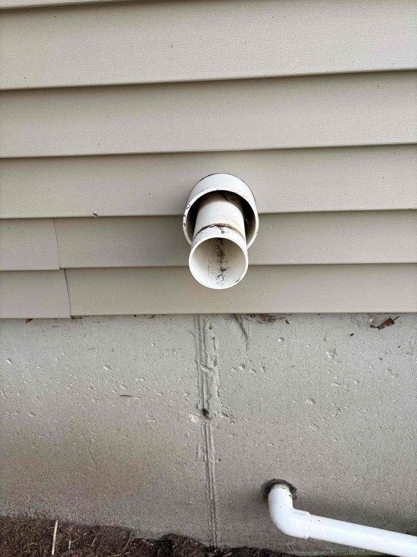 Responded to no heat call for 2008 Goodman furnace. Upon inspection, found condensate drain system experiencing drainage issues as evidenced by exterior wall staining below exhaust vent termination. Documented PVC vent pipe configuration and condensate discharge points. System evaluated for proper venting and drainage functionality to restore heating operation.
